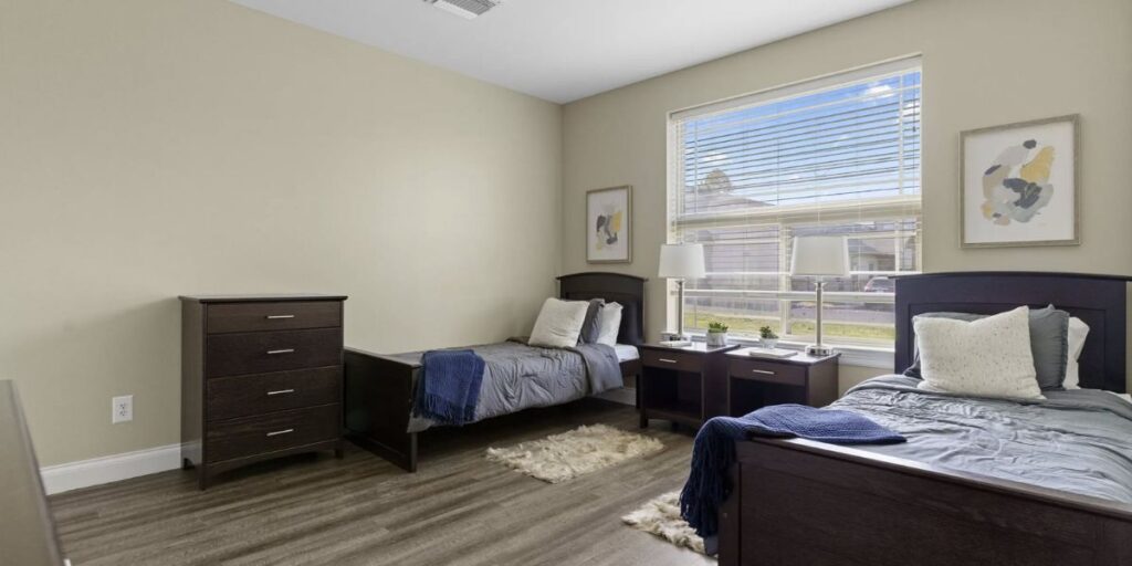 Two twin beds in a bedroom with hardwood floors. Consider shelter needs: residents, space, budget for effective furniture solutions.
