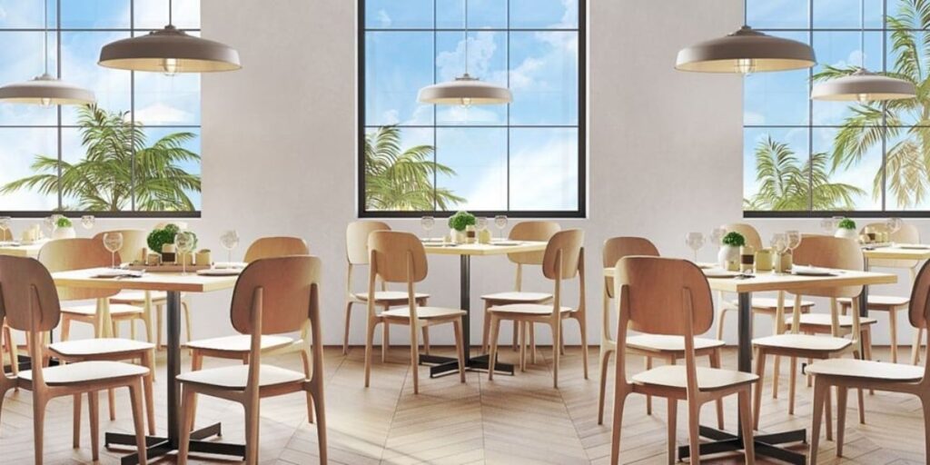 A restaurant with tables and chairs in front of large windows. Quick ship furniture for healthcare facilities, reducing waiting time significantly.