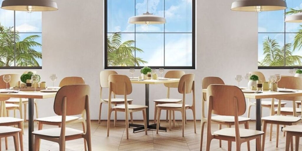 A restaurant featuring tables and chairs arranged near large windows, emphasizing a welcoming dining atmosphere.