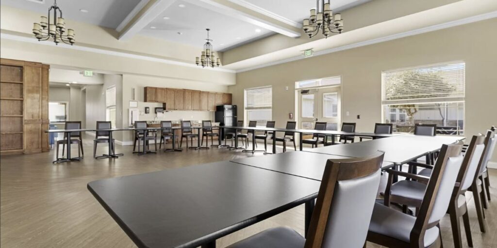 A spacious conference room featuring tables and chairs, designed for flexible seating arrangements in healthcare settings.