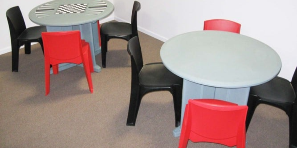 A table with chairs featuring a chess board and checkers, designed for adaptable therapeutic spaces.