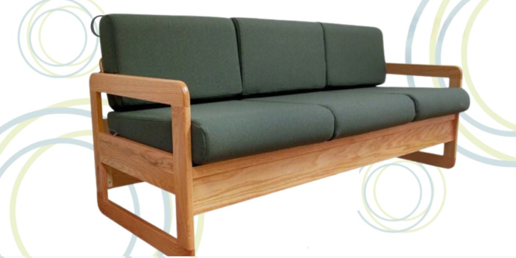 A green couch featuring wooden arms and a sturdy wooden frame, suitable for healthcare settings with durable cushions.