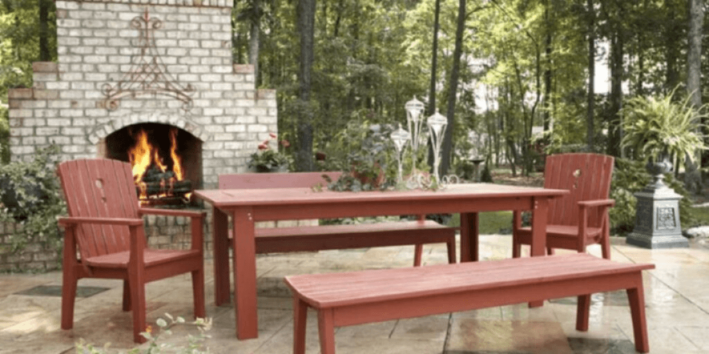 A red table and chairs positioned in front of a cozy fireplace, enhancing the inviting atmosphere of an outdoor space.
