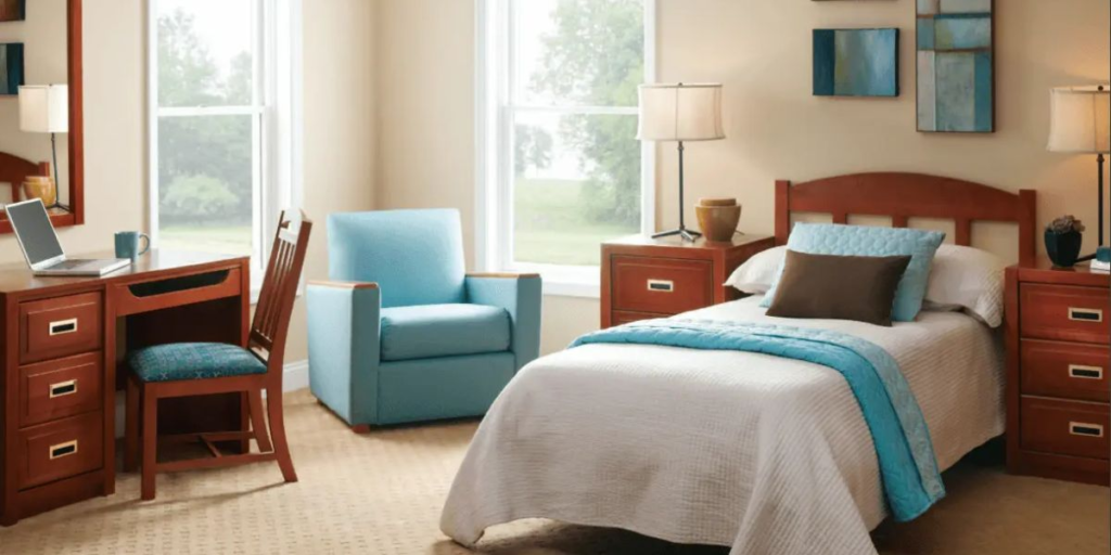 A cozy bedroom featuring a sturdy bed, a functional desk, and a comfortable chair, designed for durability and ease of maintenance.