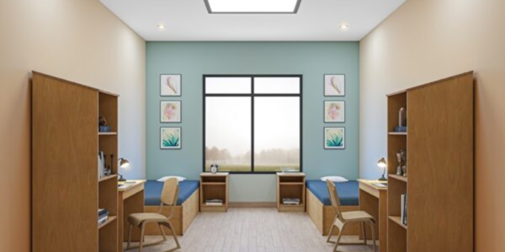 A room featuring two desks and a window, designed to promote calmness with wooden furniture for therapeutic benefits.