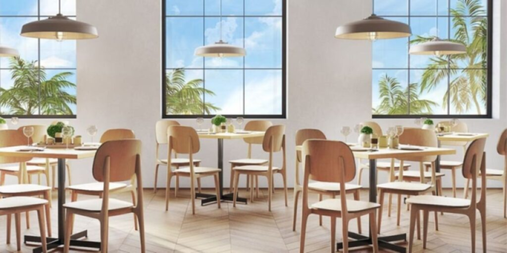 A restaurant interior featuring tables and chairs arranged near large windows, promoting an inviting dining atmosphere.