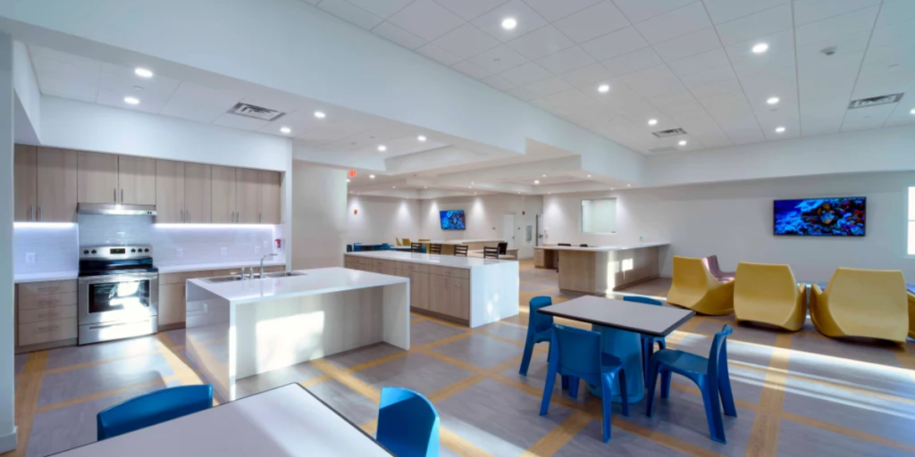 A modern office kitchen and dining area designed for high traffic, featuring sleek furniture and a welcoming atmosphere.