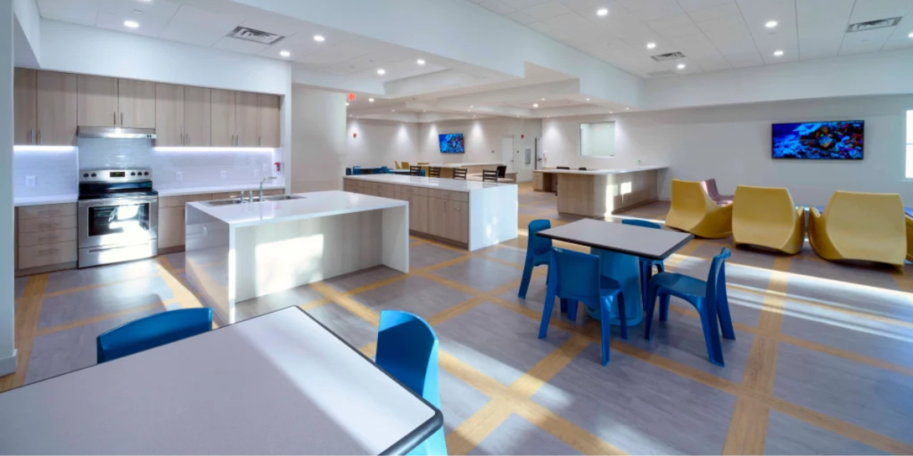 Modern office kitchen and dining area featuring versatile furniture for multi-purpose use and efficient space optimization.