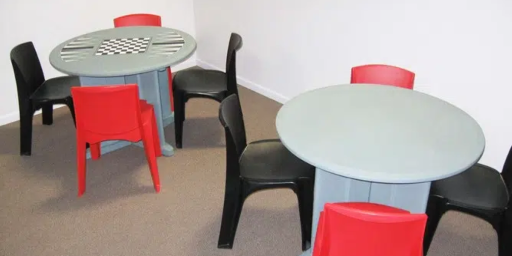 A small table surrounded by chairs, featuring a checkerboard set for a game.