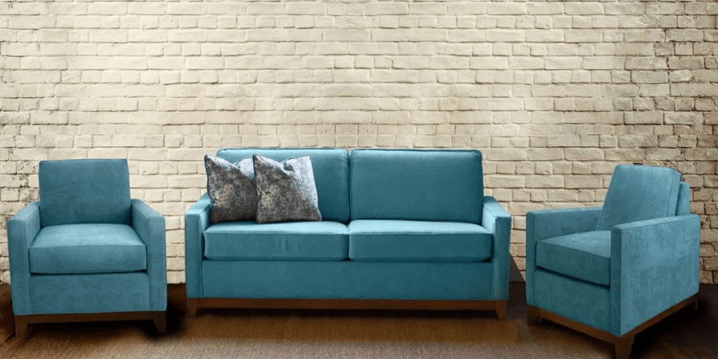 A blue couch and chair positioned in front of a textured brick wall, creating a cozy and inviting seating area.