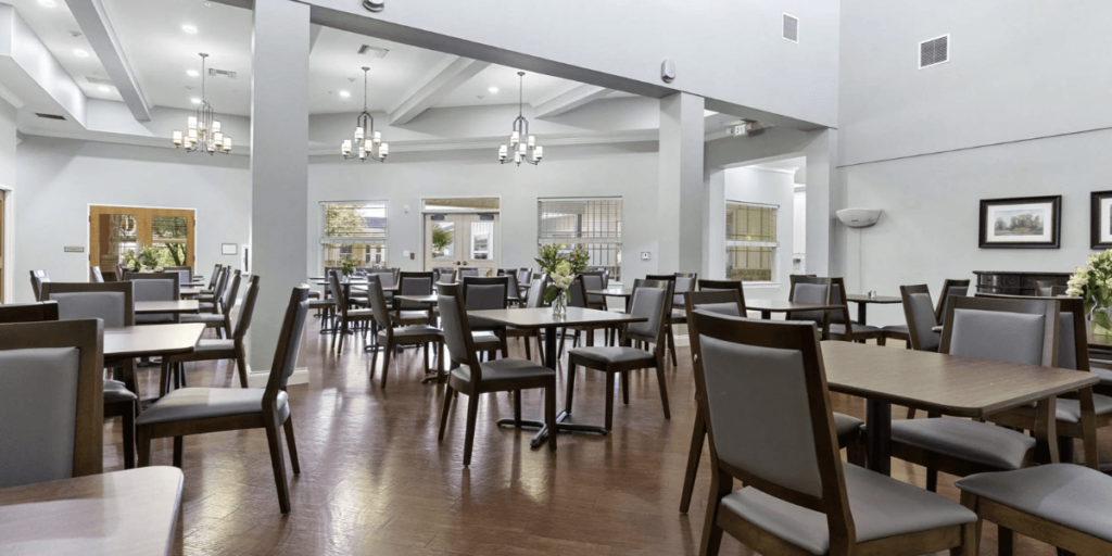 A spacious room featuring a ceiling fan and several chairs, designed for comfort in high-use environments.