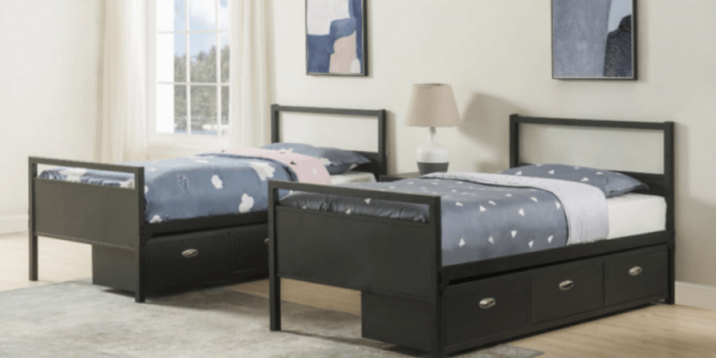 Two twin beds with drawers, featuring a blue and white bedspread, suitable for care facilities or group homes.