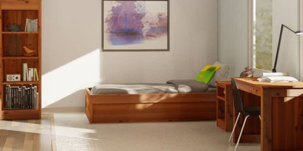 A bedroom featuring a sturdy bed, desk, and bookshelf, designed for durability in a behavioral health setting.